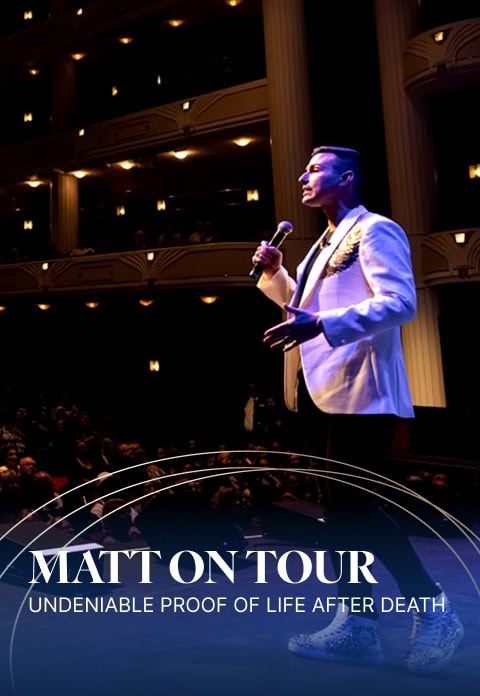 A man wearing a white blazer and holding a microphone stands on a stage in front of an audience, with the text "Matt Fraser on Tour: Undeniable Proof of Life After Death" displayed at the bottom.