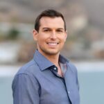 A man named Matt Fraser is smiling while standing outdoors wearing a blue shirt, with a blurred background.